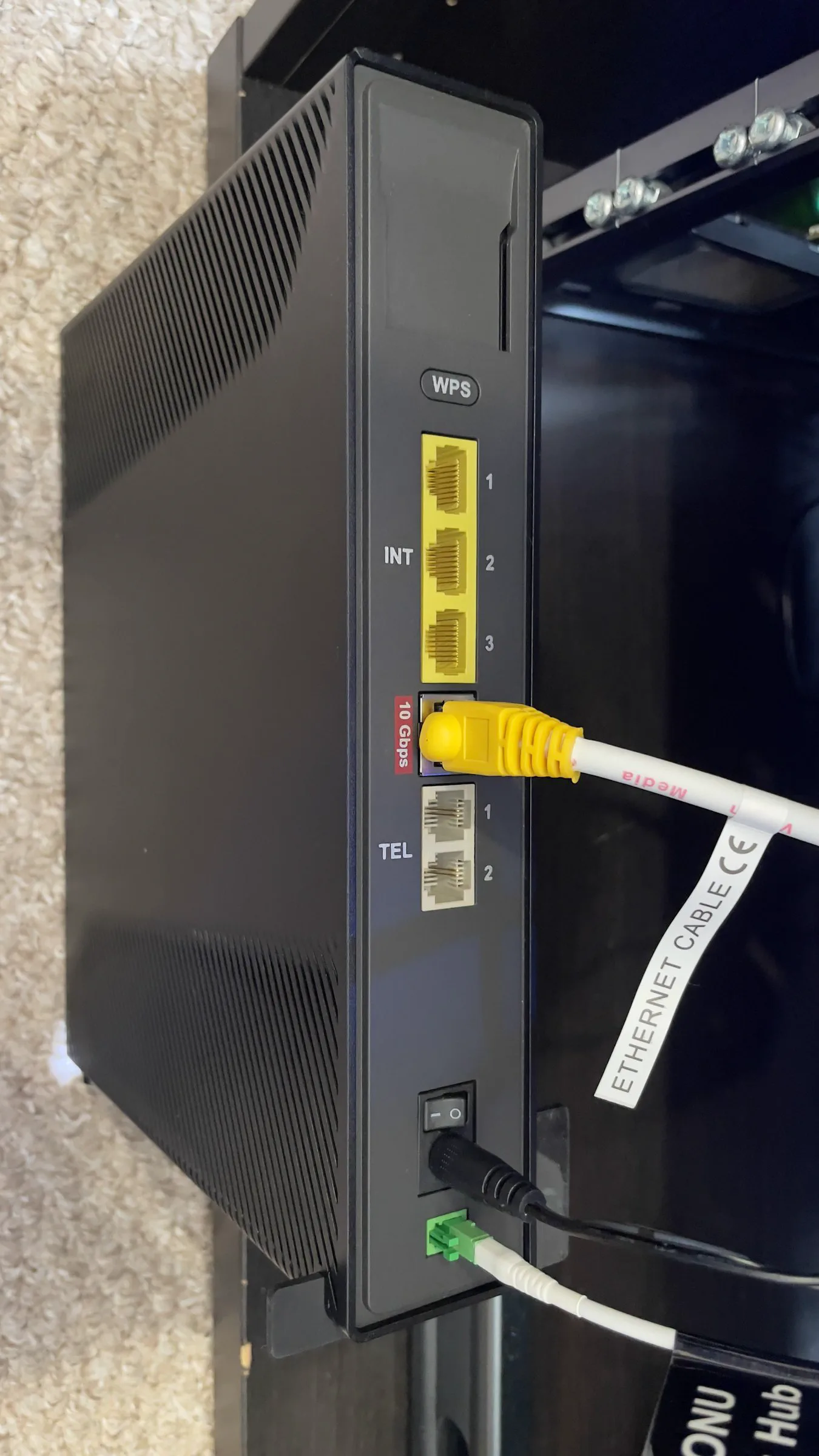 Rear panel of the Virgin Media Hub 5x showing the yellow Ethernet ports, WPS and TEL sockets, and the fibre patch lead plugged in